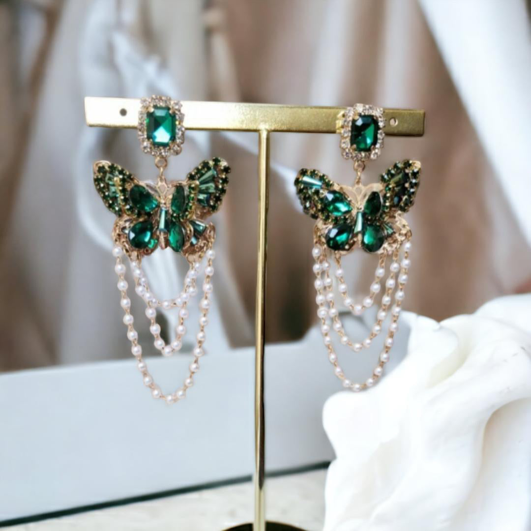 Aretes en forma de mariposa con piedras y perlas colgantes.