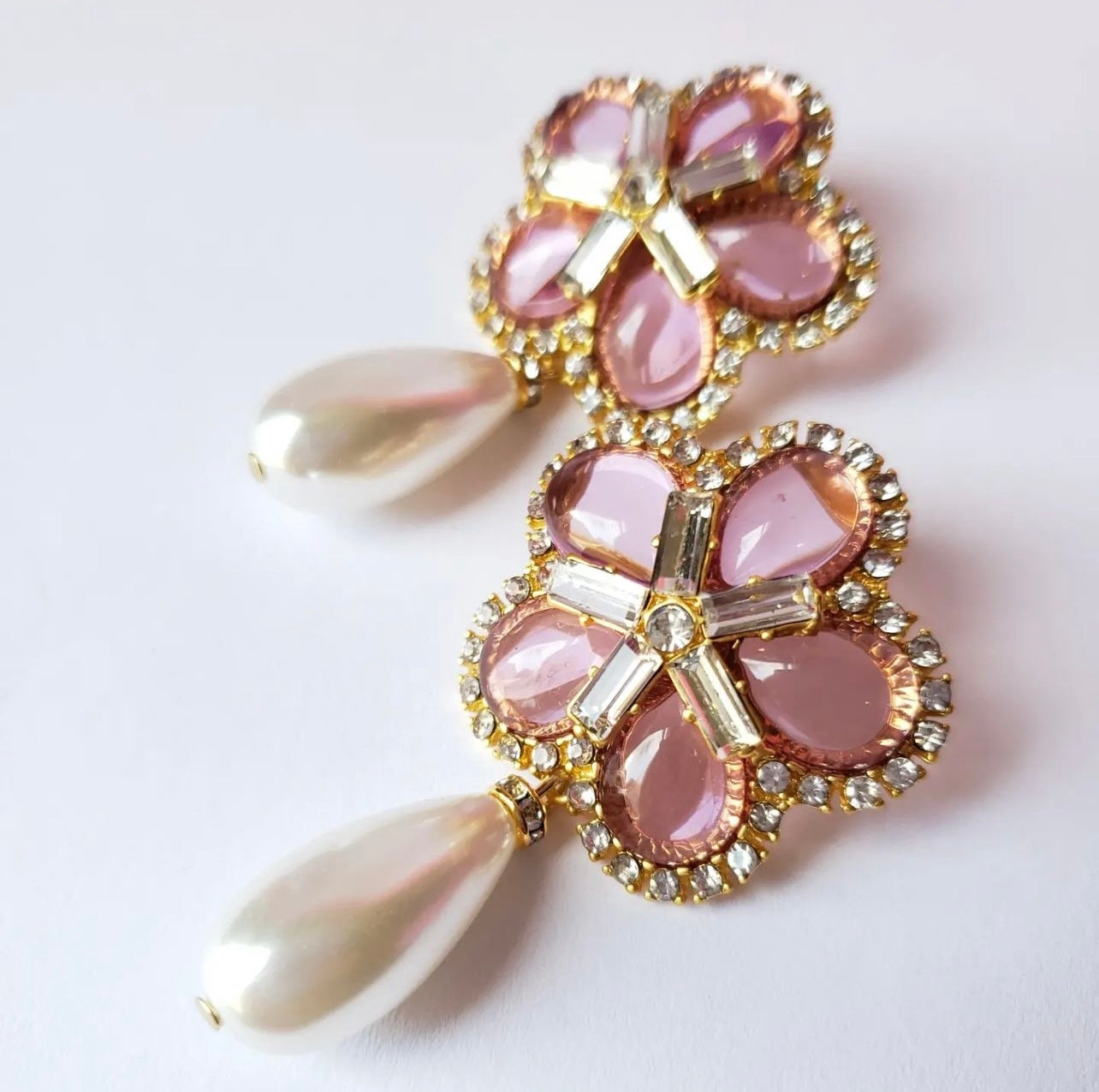 Aretes color rosa de cristales en forma de flor y perla colgante.